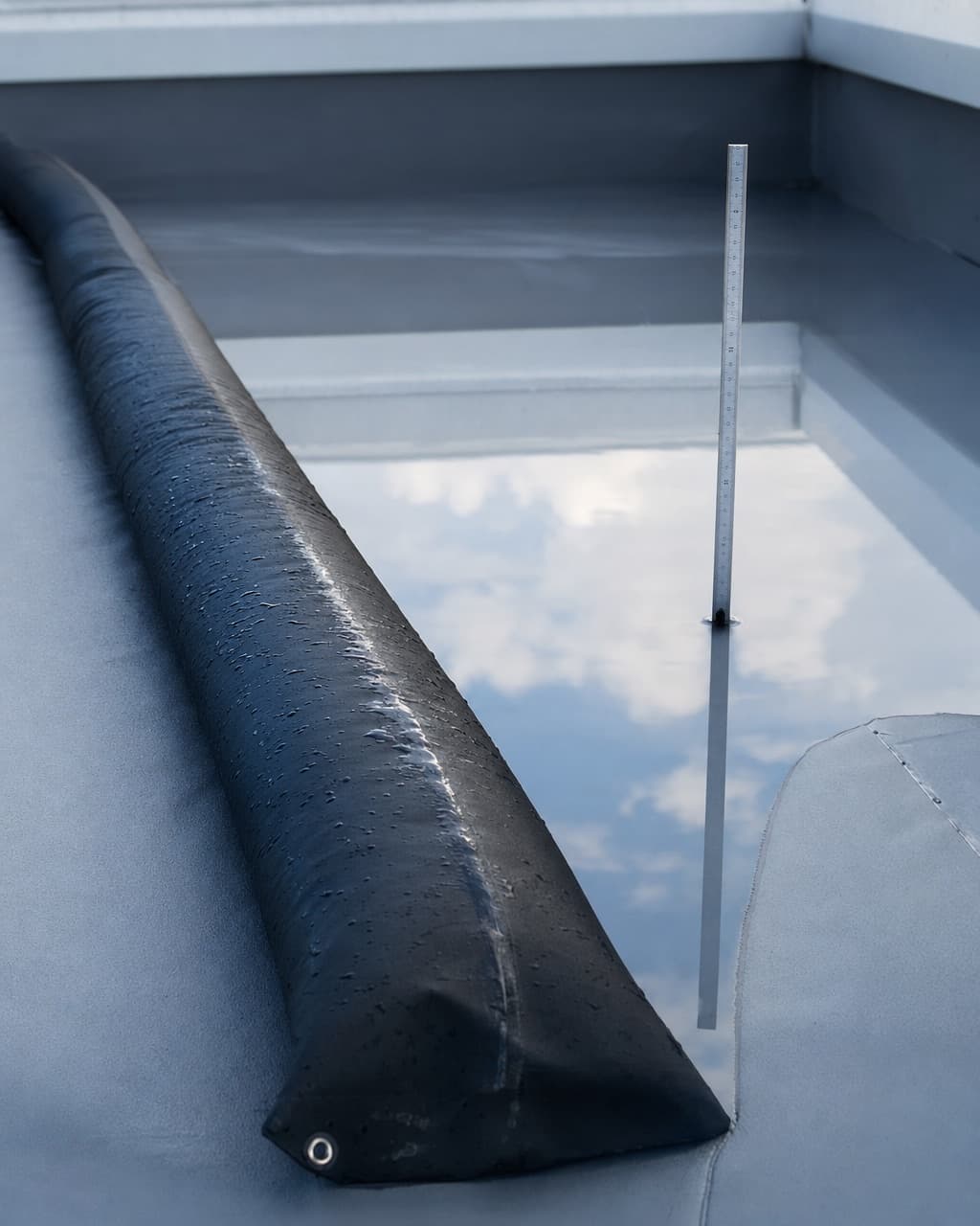 Une mise en eau contrôlée sur une toiture terrasse, l’eau retenue par un boudin gonflable avec un réglet gradué