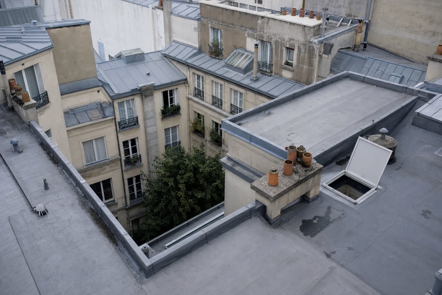 Une toiture d’immeuble en cours de relevé : plusieurs niveaux de terrasse, acrotères, trappe d’accès ouverte